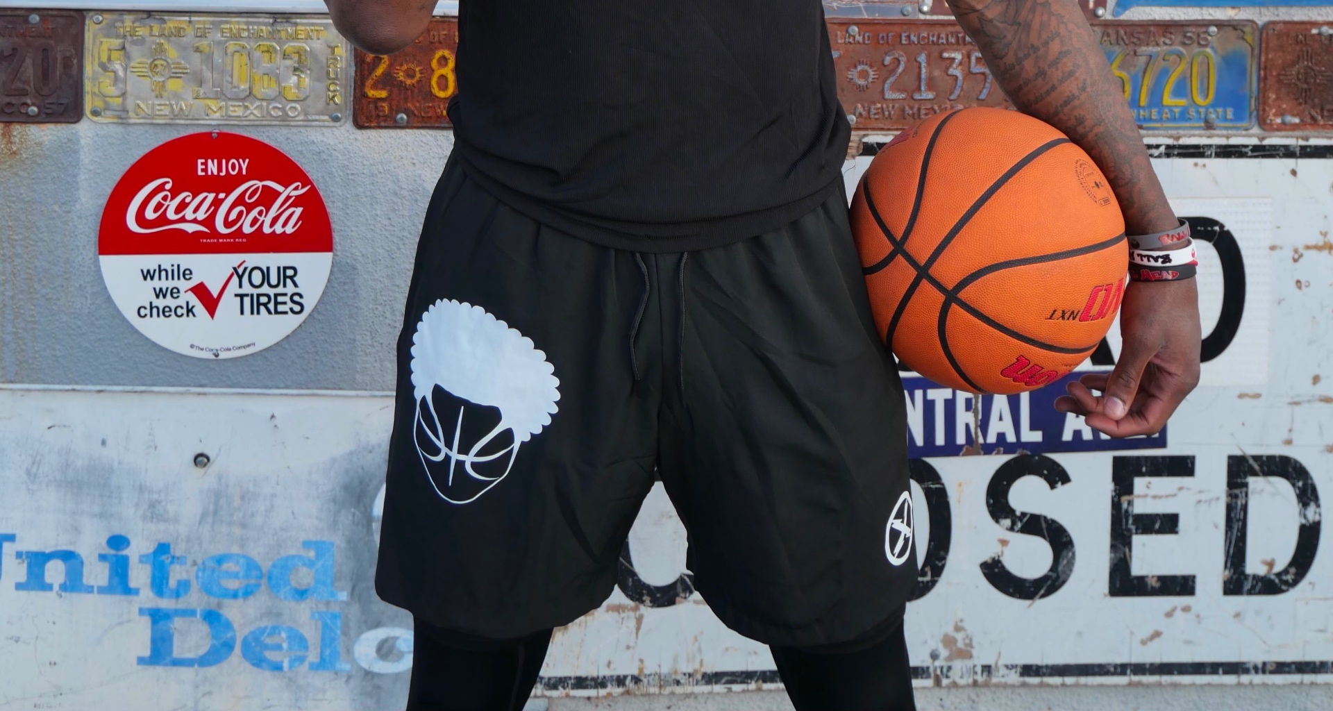 Black BallHead athletic shorts with large white afro basketball logo on the thigh, worn over black tights